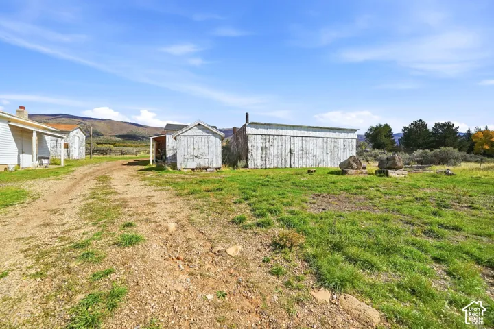 Expansive lot featuring multiple wooden outbuildings, gravel access path, and mountain backdrop