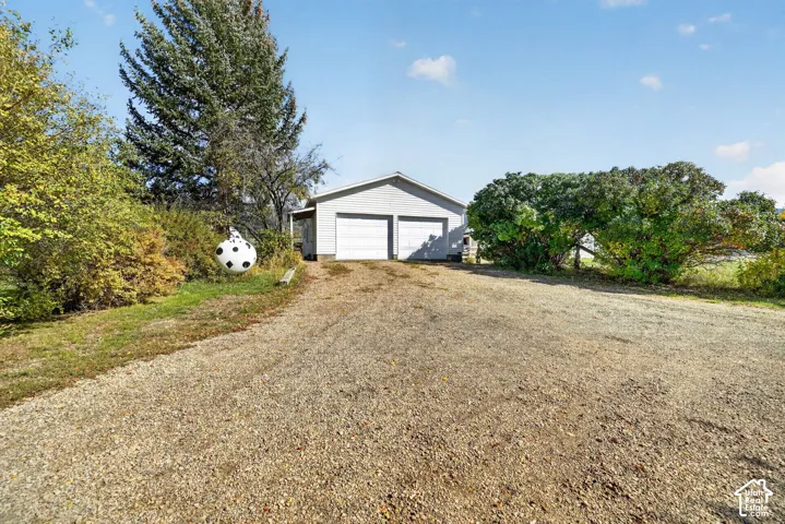 Detached two-car garage with light-colored siding and gravel driveway