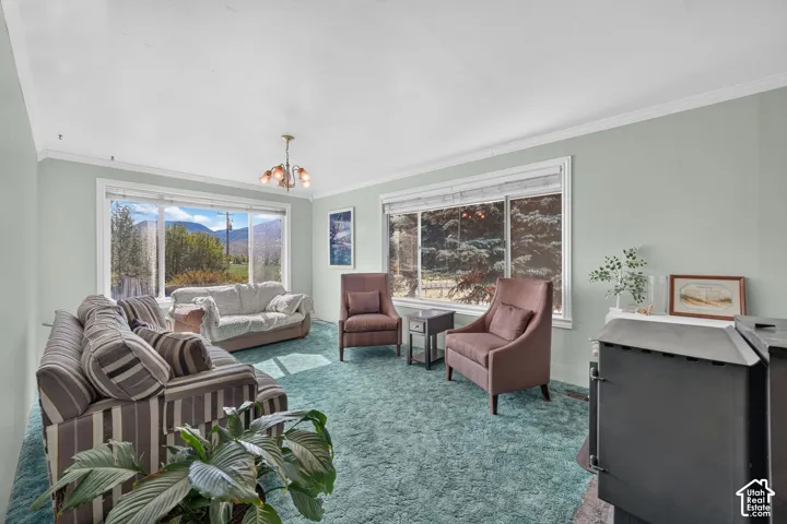 Living area featuring two large picture windows, mountain scenery, crown molding, and a built-in wood-burning stove