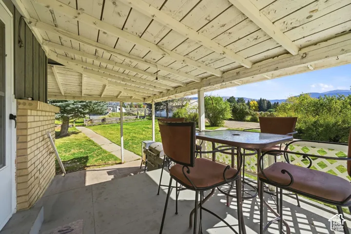 Covered patio featuring a concrete floor, beadboard ceiling, brick accent wall, and expansive mountain scenery