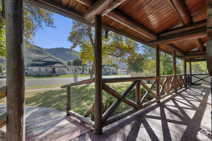 Covered porch featuring log post-and-beam construction, wood plank ceiling, and rustic log railing