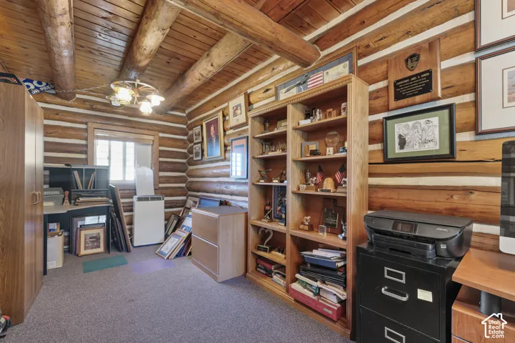 Log-walled room featuring exposed timber ceiling beams, built-in wooden shelving, and a multi-arm overhead light fixture