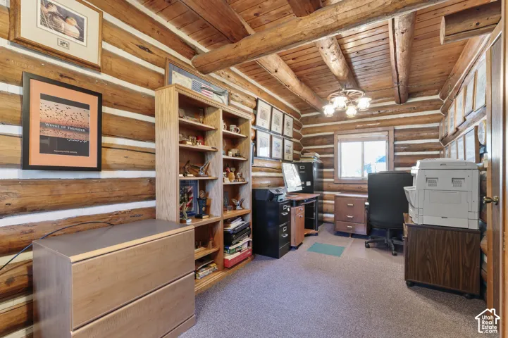 Exposed log walls featuring chinking, vaulted ceiling with exposed timber beams, built-in wooden shelving, and rustic-style overhead lighting fixture