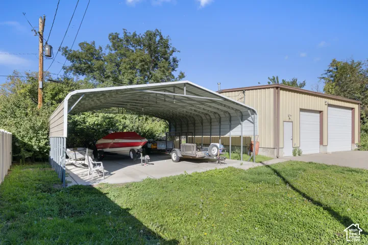 Detached metal-sided structure featuring two enclosed garage bays and an expansive attached open-air carport on a concrete slab