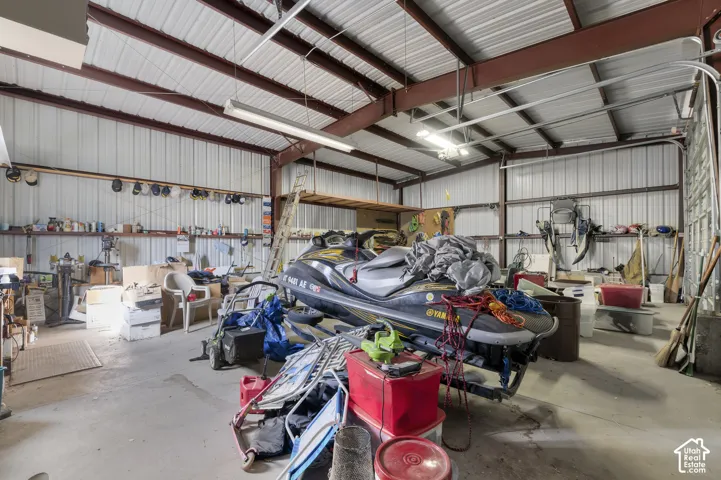 Large-span workshop featuring high ceilings, exposed steel beams, corrugated metal walls, and concrete flooring