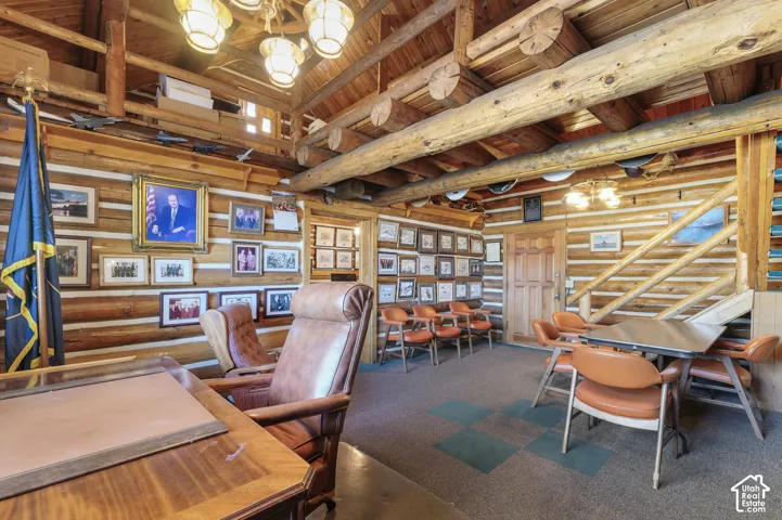 Exposed log wall construction, heavy timber ceiling beams, and integrated wood staircase with railings