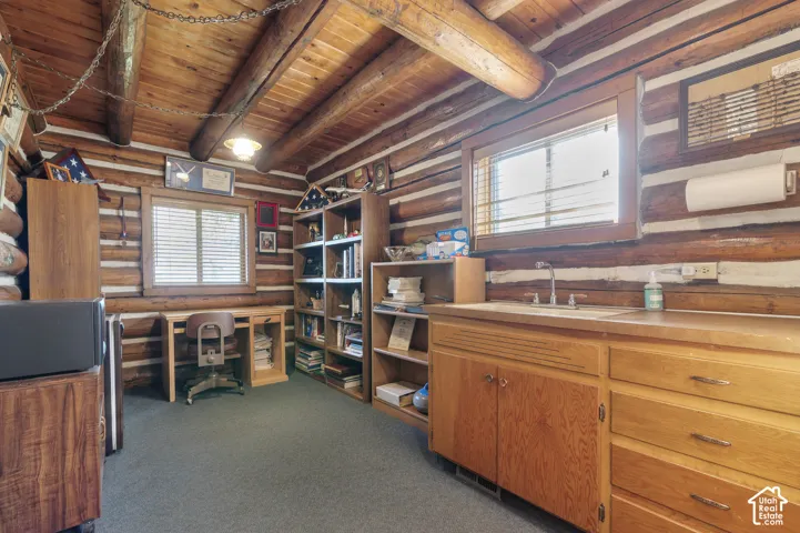Log-style walls and exposed timber ceiling beams, built-in wooden cabinetry with stainless steel hardware, and dual windows