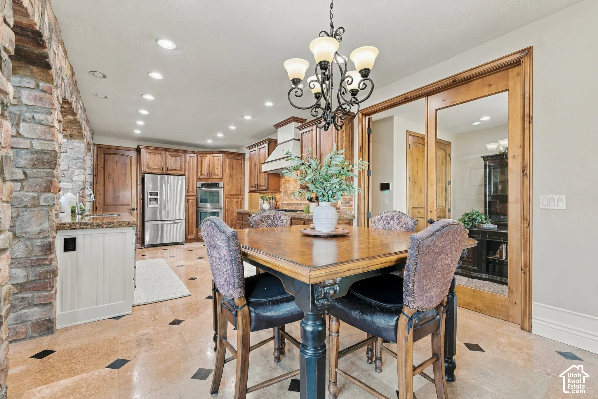 Kitchen featuring recessed lighting, stainless steel appliances, stone tile flooring with decorative inlay, and wood-framed glass French doors.