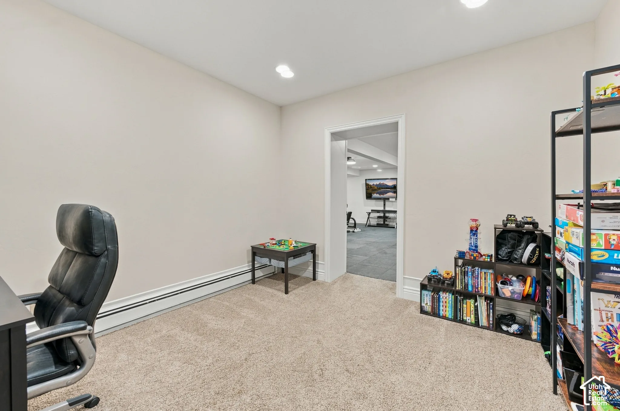 Neutral-toned interior space featuring recessed ceiling lighting, wall-to-wall carpeting, and a cased doorway leading to an additional carpeted area.