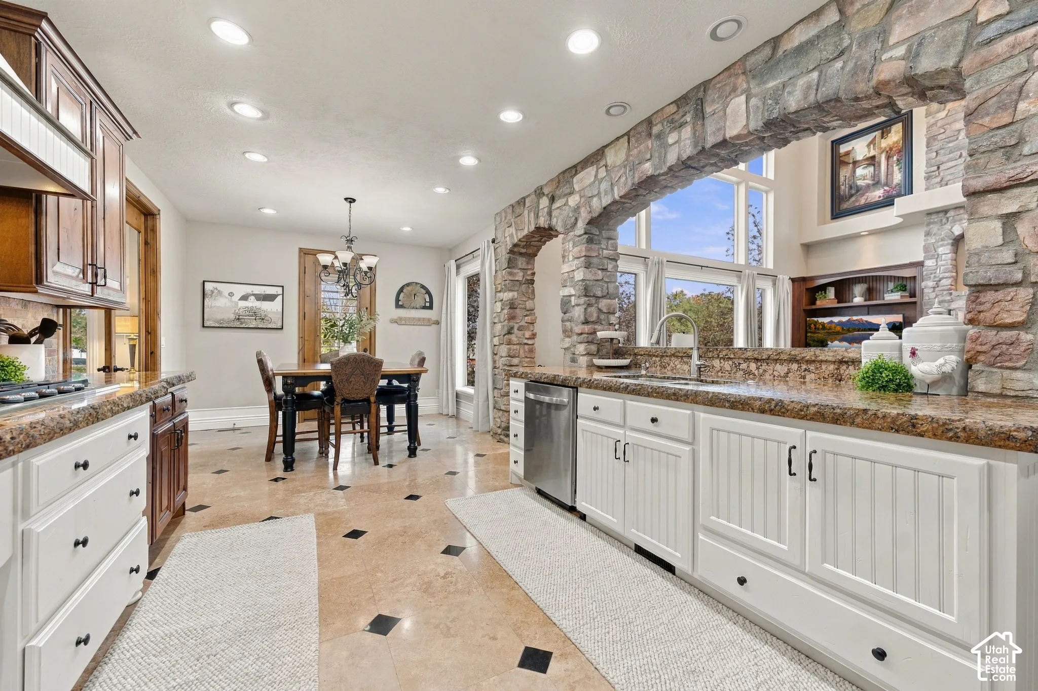 Kitchen with custom cabinetry with dual-tone finish, stone-surface countertops, recessed lighting, and tile flooring with decorative inlay.