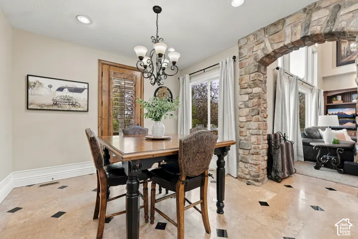 Dining area featuring natural stone tile flooring with diamond-patterned inlay, recessed lighting, and a decorative wrought iron chandelier.