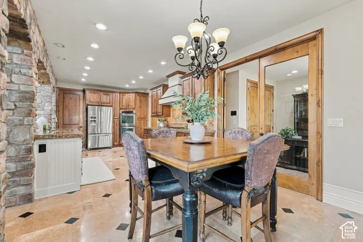 Kitchen featuring recessed lighting, stainless steel appliances, stone tile flooring with decorative inlay, and wood-framed glass French doors.