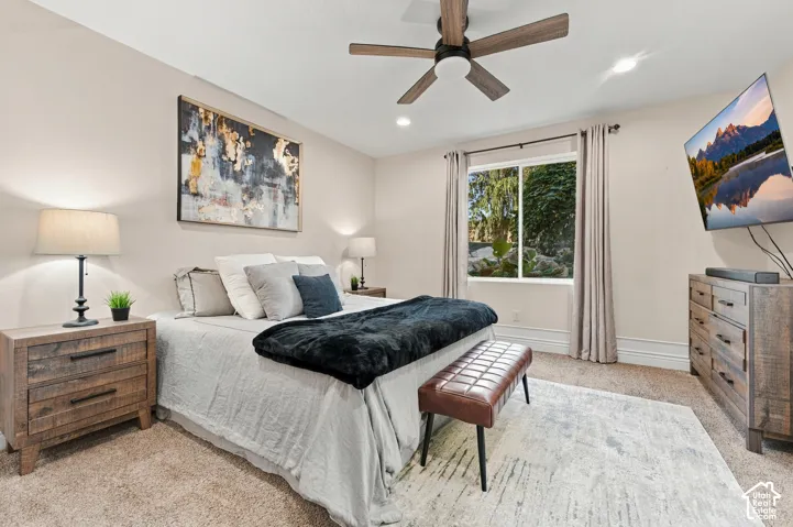 Neutral-toned bedroom featuring carpeted flooring, a multi-blade ceiling fan with integrated lighting, recessed ceiling lights.