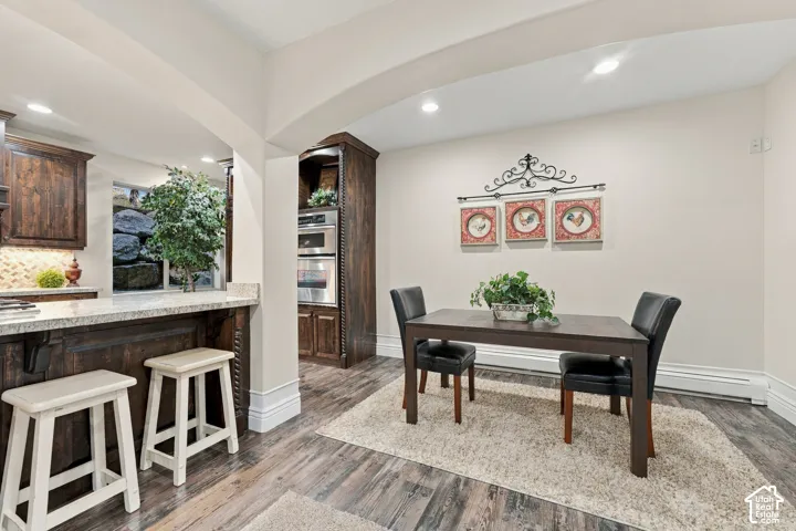 Dark wood-finish cabinetry, built-in double wall ovens, granite countertops, recessed lighting, and wood-finish flooring.