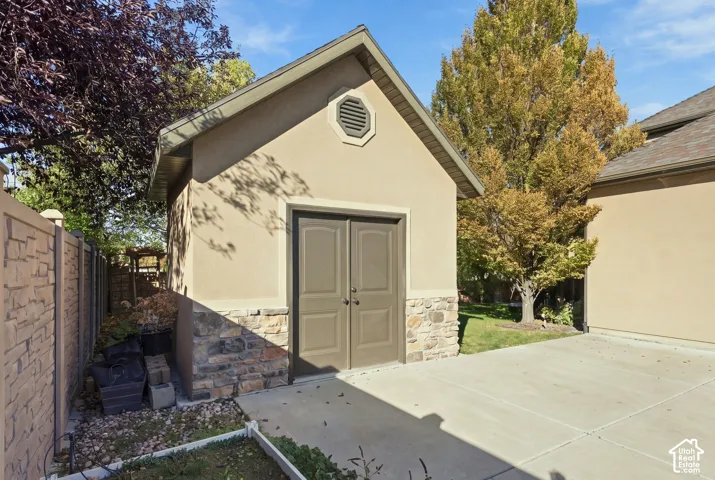 Detached storage structure featuring a gable roof, stucco exterior, stone base, and double-entry doors. Built with the same quality as a garage.