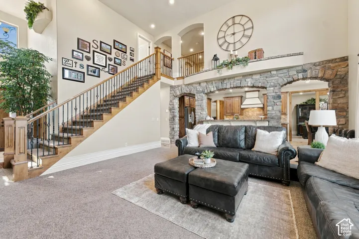 Open-concept interior, staircase with wood banister and iron balusters, recessed lighting, and high ceilings.