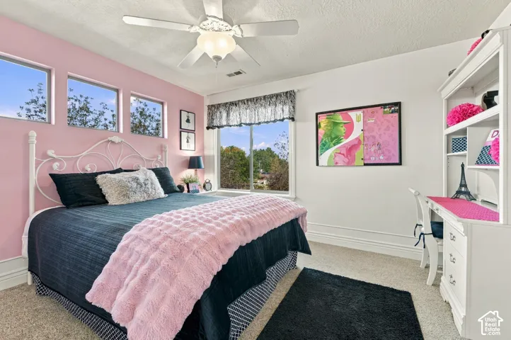 Bedroom featuring carpeting, a white ceiling fan with integrated lighting, a sliding window, and three high-set rectangular windows.