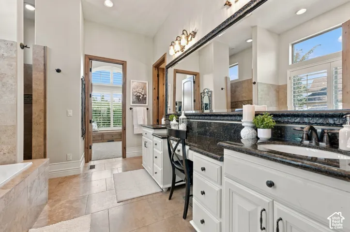 Bathroom featuring a dual-sink vanity with granite countertops, custom white cabinetry, tile flooring, and a full-width custom framed wall mirror.