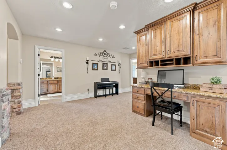Built-in desk area featuring wood cabinetry, stone countertops, recessed lighting.