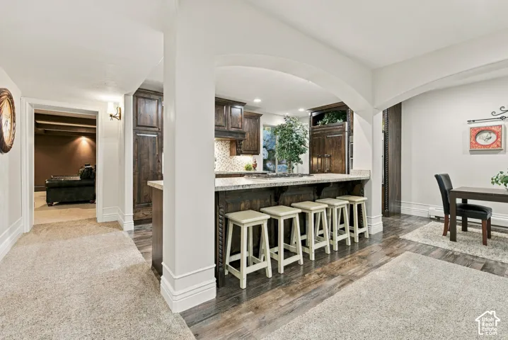Kitchen featuring dark-stained wood cabinetry, stone countertops, a breakfast bar with archway structural detailing.