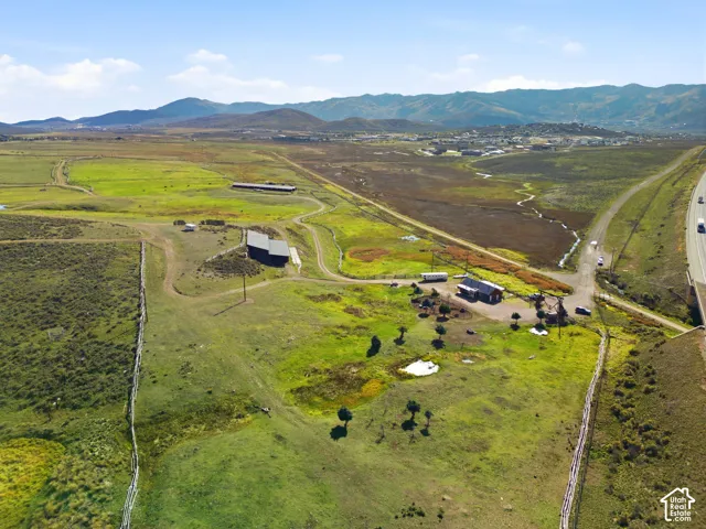 Expansive acreage featuring rolling terrain, multiple outbuildings, fenced boundaries, and prominent mountain backdrops