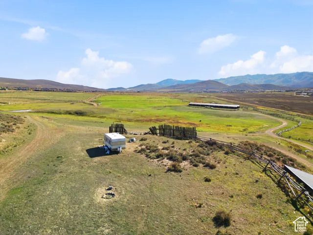 Expansive acreage featuring rolling terrain, mountain backdrops, and perimeter wood fencing