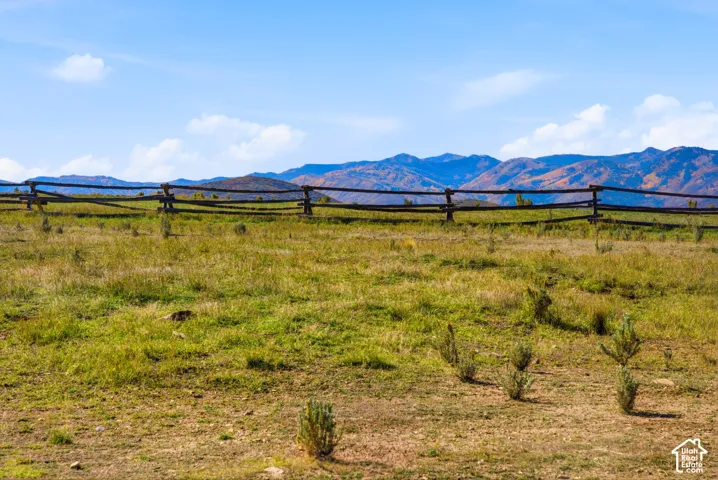 Expansive open acreage featuring split-rail wood fencing and prominent mountain scenery