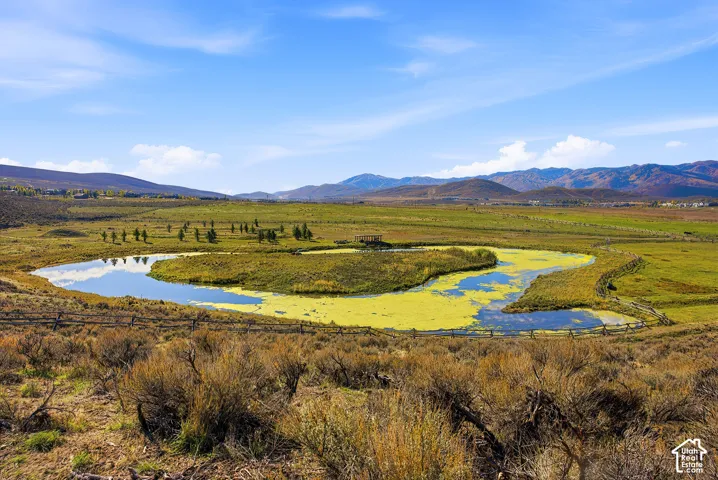 Expansive acreage featuring a natural pond, split-rail perimeter fencing, and a mountain backdrop