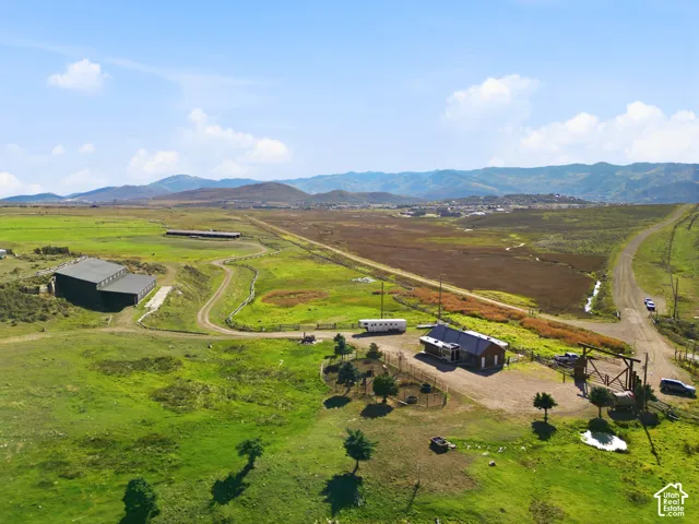 Expansive acreage featuring mountain scenery, large-scale metal barn structure, gated gravel entrance, and rural topography