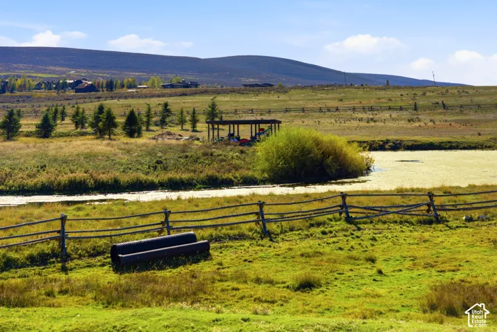 Expansive acreage featuring a natural pond, split-rail fencing, and prominent mountain backdrop
