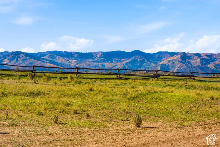 Expansive open acreage featuring a natural landscape, traditional split-rail timber fencing, and a backdrop of mountain ranges