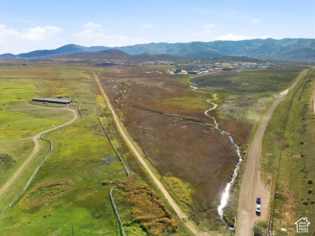 Expansive acreage featuring natural stream, mountain backdrop, and dirt road access