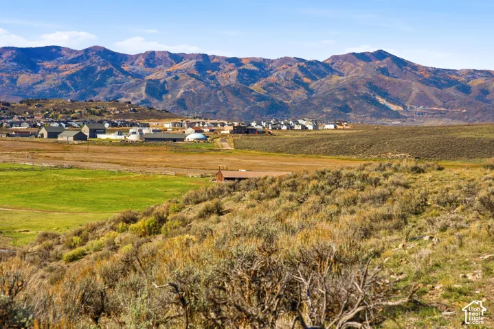 Expansive landscape featuring rolling terrain, natural vegetation, and prominent mountain backdrops
