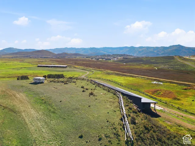 Expansive acreage featuring a modern single-story residence with a shed roof, mountain backdrop, and rail fencing