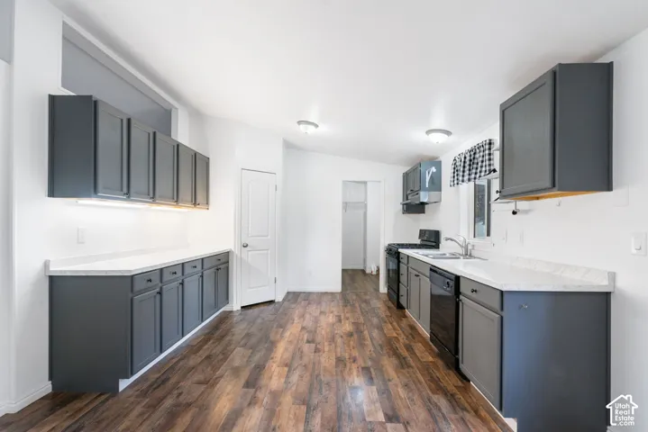 Kitchen featuring dark-toned cabinetry, light-colored countertops, wood-finish flooring, recessed lighting, and built-in appliances