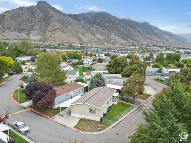 Corner lot property featuring a single-level structure, metal carport, chain-link perimeter fencing, and mountain backdrop