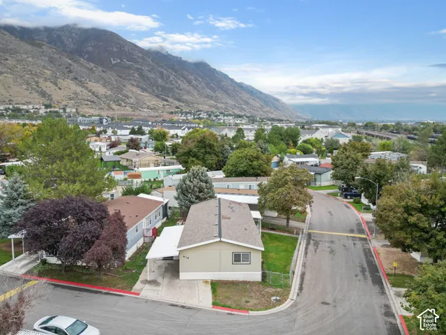 Single-level residence featuring a covered carport, pitched composition shingle roof, neutral exterior siding, and mountain backdrop
