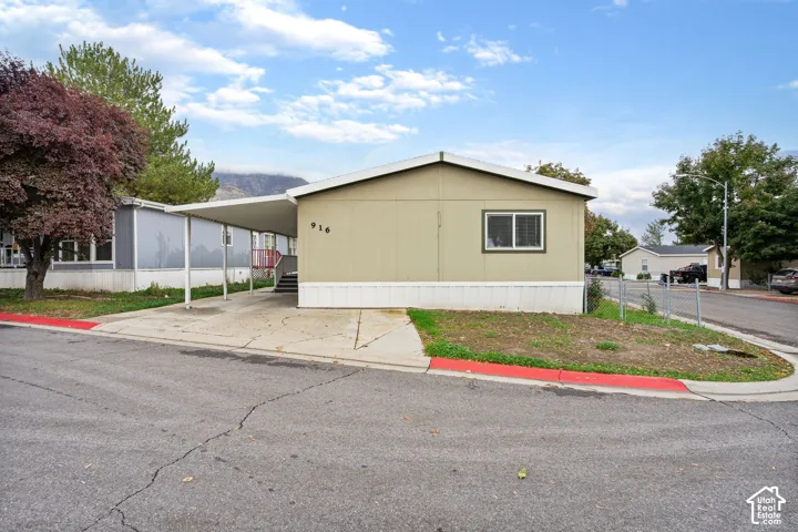 Single-story exterior featuring light-toned vertical siding, a covered carport, and mountain backdrop