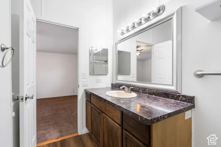 Vanity featuring dark wood cabinetry, integrated countertop with oval basin, wall-mounted mirror, and multi-bulb light fixture