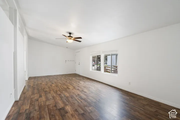 Vaulted ceilings, wood-finish flooring, and a central ceiling fan, accented by dual-pane sliding windows