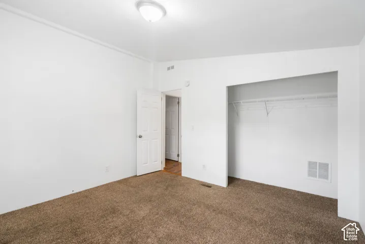 Interior room featuring wall-to-wall carpeting, neutral paint, a ceiling-mounted light fixture, and a built-in closet with wire shelving
