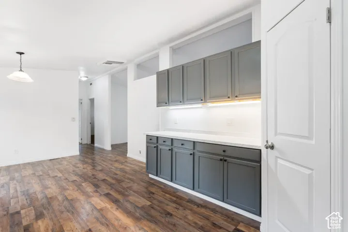 Built-in cabinetry featuring slate-gray shaker-style doors, stone-finish countertops, under-cabinet lighting, wood-finish flooring, and transom windows