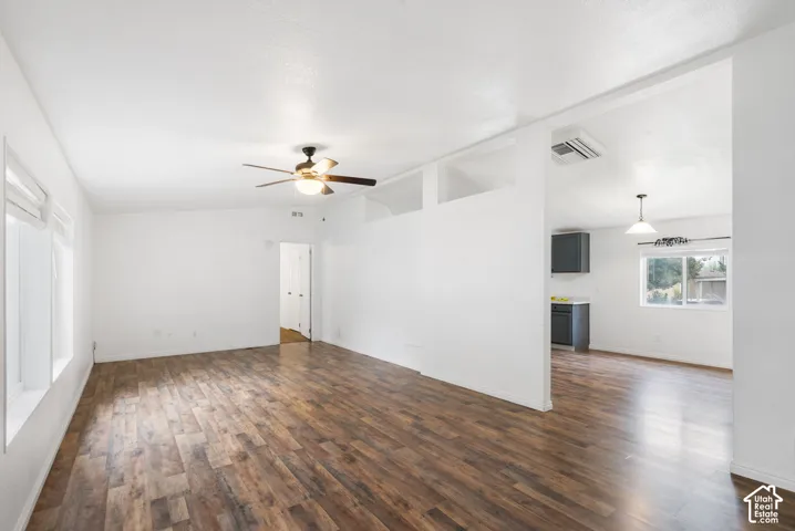 Living area featuring wood-finish flooring, recessed wall cutouts, a ceiling fan with integrated lighting, and neutral wall tones