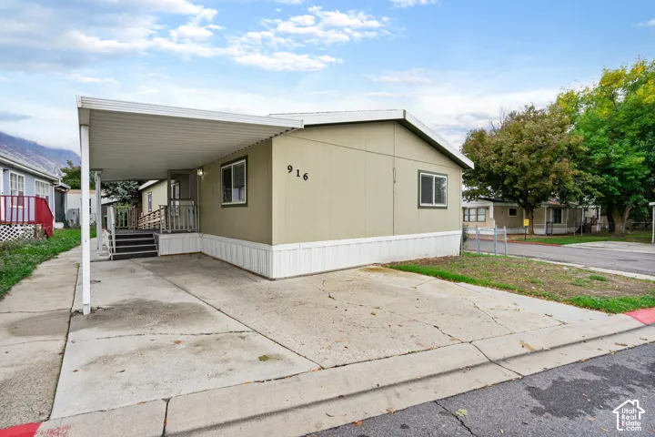 Exterior featuring a covered carport, concrete driveway, and stairs with metal railings
