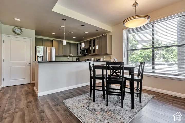Kitchen featuring gray cabinetry, stainless steel appliances, dark stone-finish countertops, wood-finish flooring, and pendant lighting