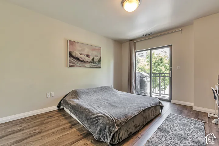 Neutral-toned interior featuring wood-finish flooring, a flush-mount ceiling light, and sliding glass doors providing access to a private balcony