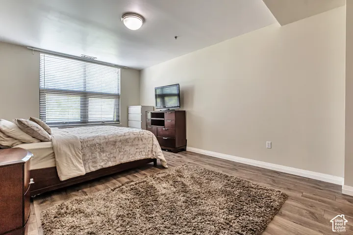 Neutral-toned interior featuring wood-finish flooring, a large window with horizontal blinds, and a circular flush-mount ceiling light fixture