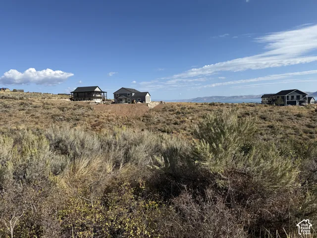 Expansive natural landscape with native brush and shrubbery, featuring prominent water scenery and distant mountain topography