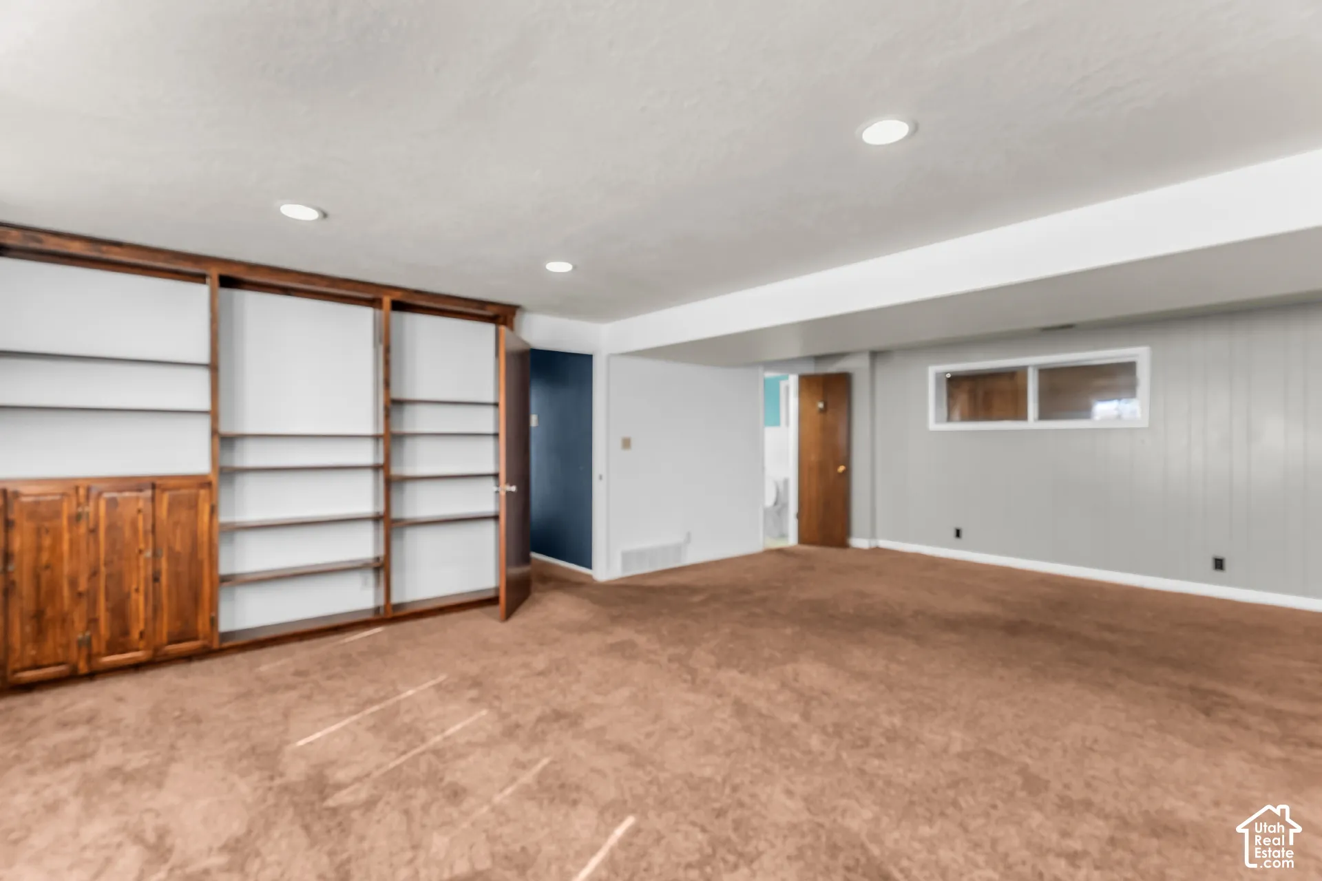Built-in wood shelving unit, recessed lighting, wall-to-wall carpeting, and horizontal sliding window