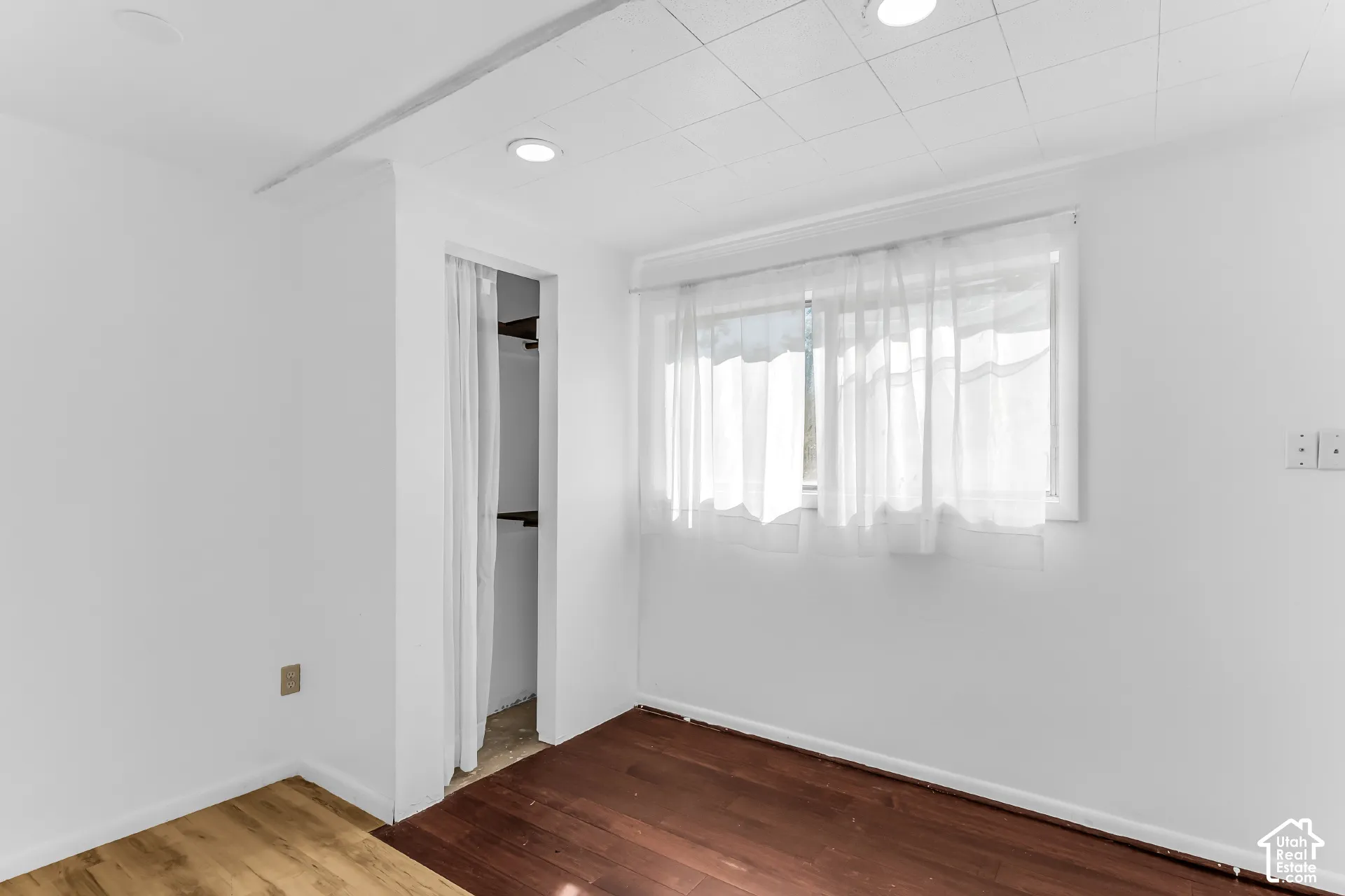 Interior space featuring recessed lighting, paneled ceiling, wood-finish flooring, and a window with white trim